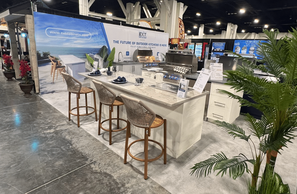 a wide shot of an extcabinets showcase with multiple white outdoor kitchens, stainless steel grills, and decorative furniture